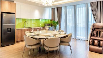 A modern kitchen with a built-in refrigerator, a dining area with a round table and chairs, and a massage chair.