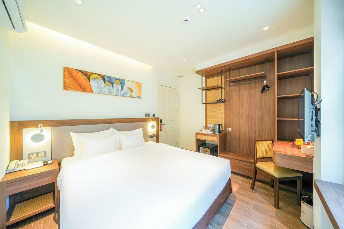 Une chambre d’hôtel avec un grand lit, des tables de chevet avec des lampes, un bureau avec une chaise et des étagères intégrées.