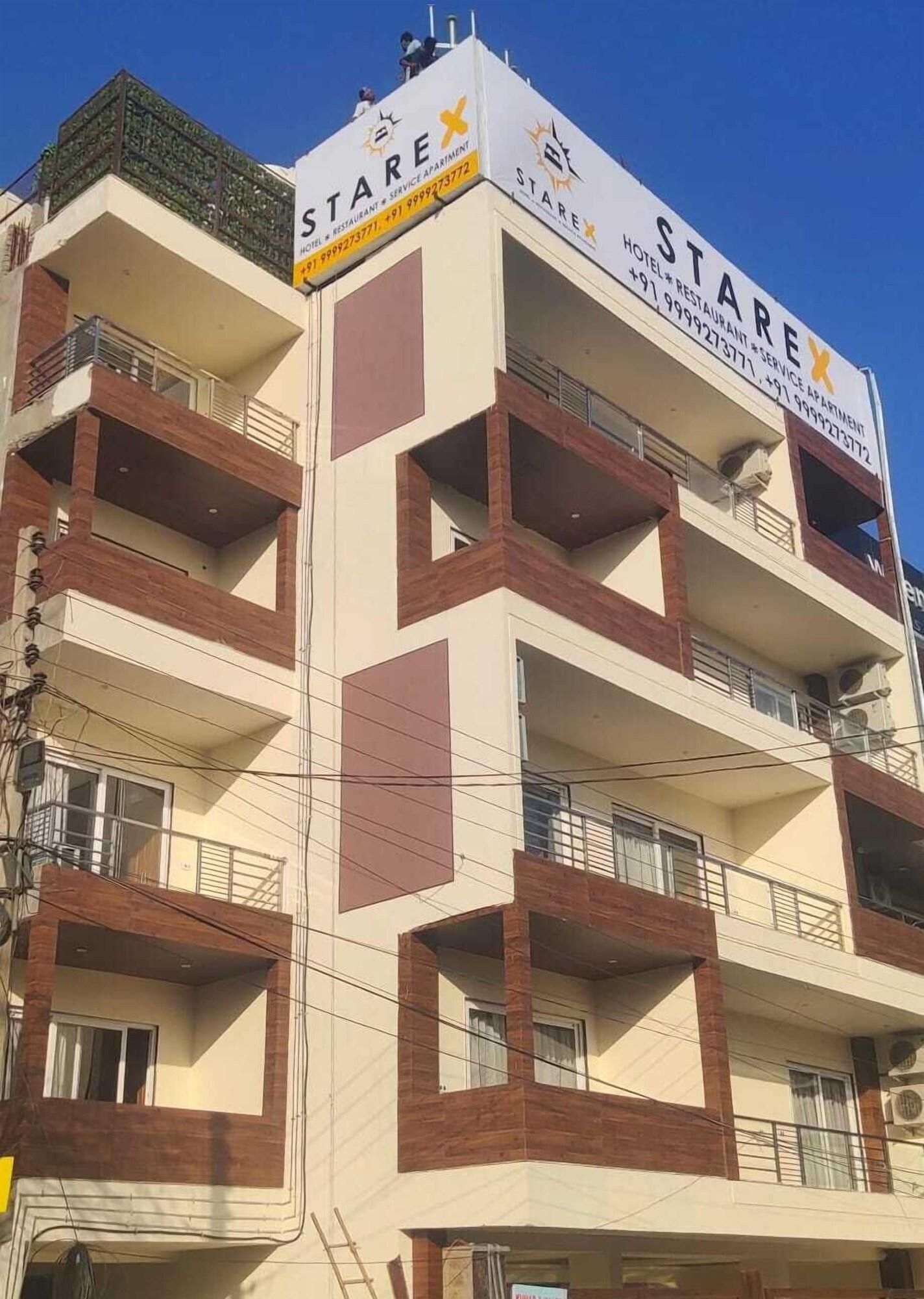 Un edificio de varios pisos con balcones, un letrero que dice 'STARE HOTEL RESTAURANT SERVICE APARTMENT' y número de contacto.
