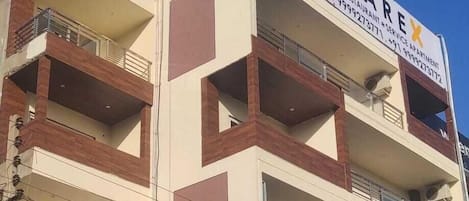 Un edificio de varios pisos con balcones, un letrero que dice 'STARE HOTEL RESTAURANT SERVICE APARTMENT' y número de contacto.