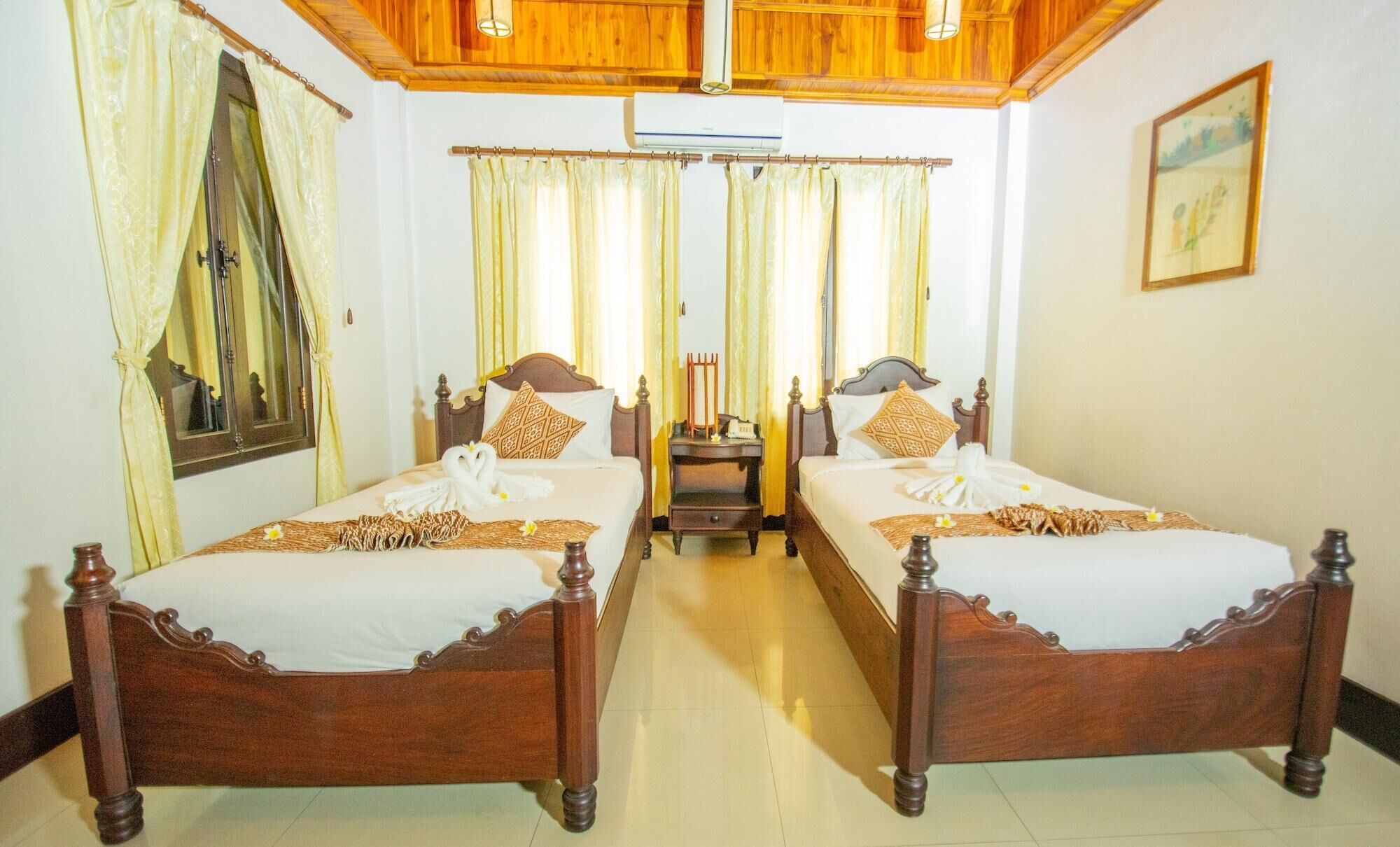 A hotel room with two wooden beds, a wooden ceiling, and a small table between the beds.