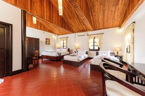 A hotel room with two beds, a wooden ceiling, and a tiled floor.