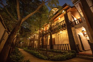 A traditional building with a wooden balcony and a pathway lined with trees.