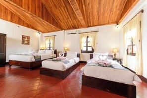 A hotel room with three wooden beds, a tiled floor, and a wooden ceiling.