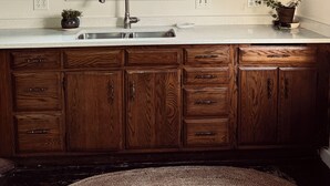 A kitchen with wooden cabinets, a stainless steel sink, and a window with a view of trees. - Chic Dunes Cottage W/ HOT TUB near Warren Dunes / Lake MI! (Shorewood-Tower Hills-Harbert)