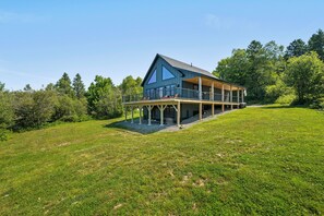 A two-story house with a balcony and a covered porch. - Golden Sunset | New Construction in The Overlook | Close to Saddleback | Rangeley Lake Views! (Rangeley)