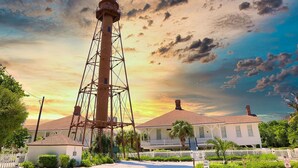 A lighthouse with a metal framework, a white building with a red roof, and a white picket fence. - Light bright airy loggerhead cay unit 314 New! (Sanibel)