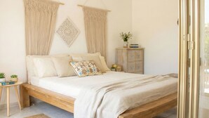 A bedroom with a wooden bed, beige bedding, a small bedside table with a plant, and a cabinet with decorative items. - La Meravigliosa Sardegna by Interhome (Santa Maria Navarrese)