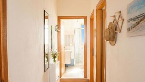 A narrow hallway with wooden doors, a woven rug, and a framed mirror. - La Meravigliosa Sardegna by Interhome (Santa Maria Navarrese)