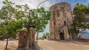 A stone building with a circular tower, a tree in front, and a bench to the right. - La Meravigliosa Sardegna by Interhome (Santa Maria Navarrese)