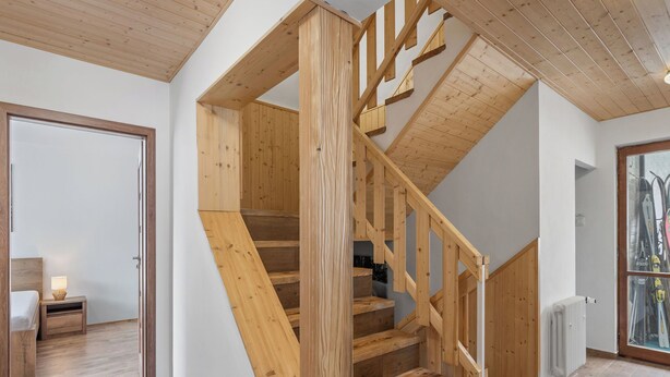 Un escalier en bois au design moderne, menant à l’étage supérieur.