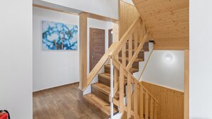 Un escalier en bois menant à un deuxième étage, une porte en bois et un tableau encadré accroché au mur.