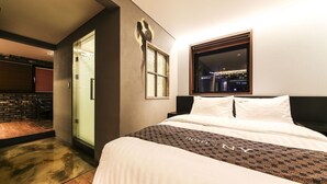 A hotel room with a bed, a window with a city view, a door, and a wall-mounted artwork. - Yeongdeungpo Station New York Hotel (Seoul)