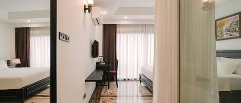 A hotel room with a bed, a desk, a chair, a TV, and a painting on the wall.