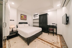 Ein Hotelzimmer mit Bett, Schreibtisch, Stuhl, Fernseher, einem Gemälde und einem Badezimmer mit Duschvorhang.