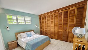 Una camera da letto con un letto, un'armadio in legno, una lampada da comodino e una finestra.