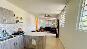 Una cucina moderna con piani in granito, forno integrato e zona pranzo con divano scuro e televisione.