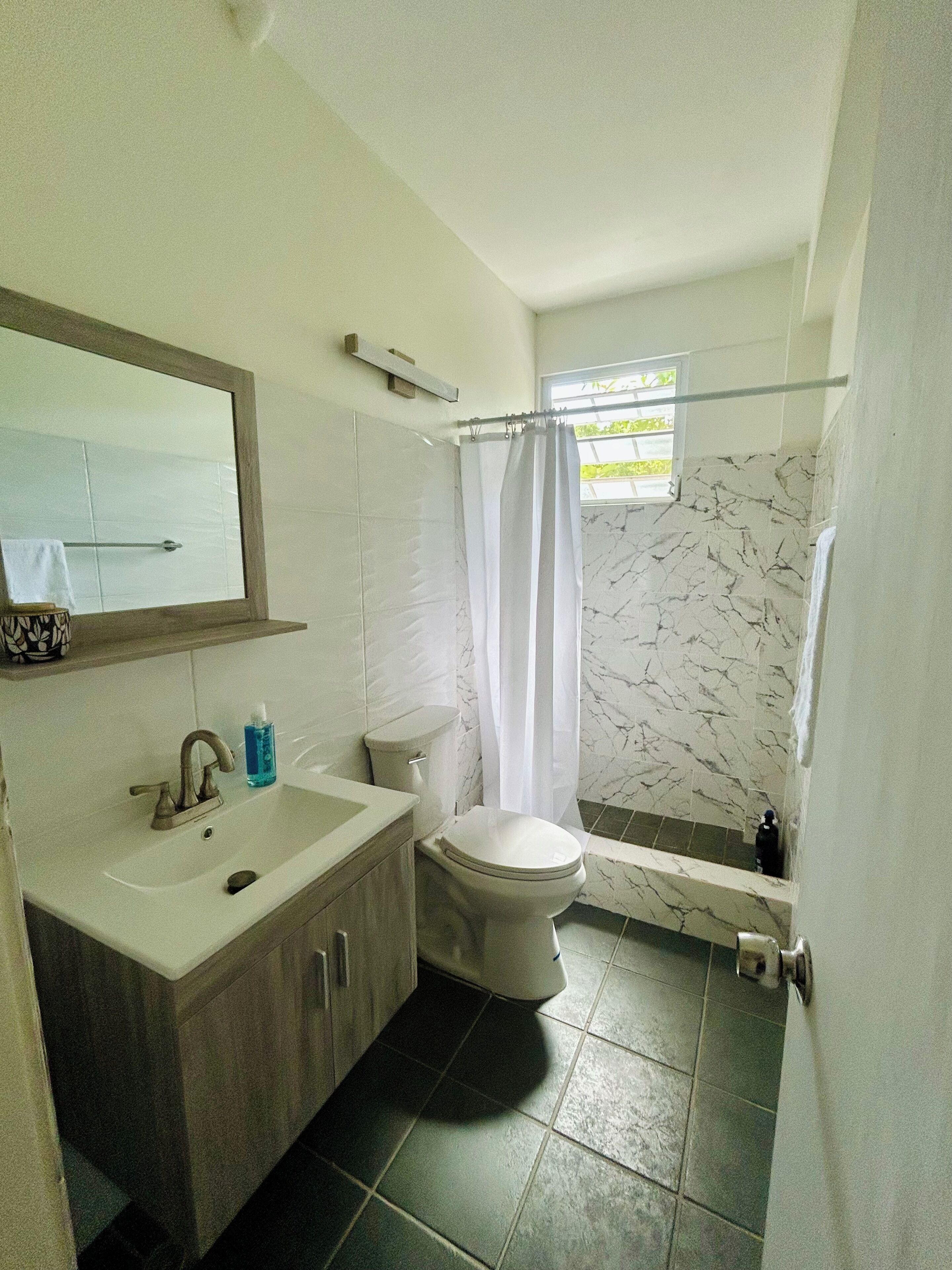 A bathroom with a sink, toilet, and shower area.