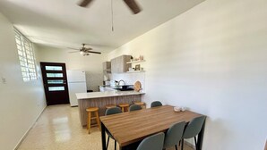 Una cucina moderna con isola centrale, sgabelli da bar e tavolo da pranzo con sedie.