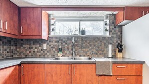 A kitchen with wooden cabinets, a stone backsplash, and a window above the sink. - Spacious 2BR Bsmt Apt w/ Free Parking (Mississauga)