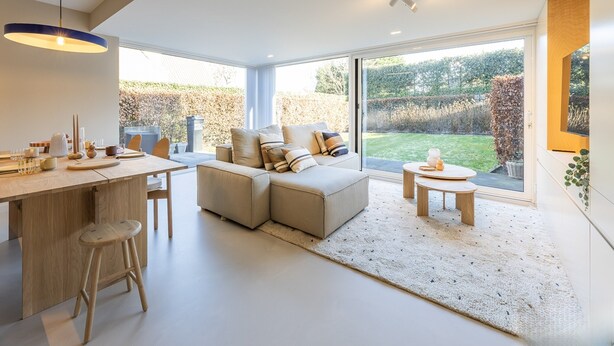 Une cuisine moderne avec un coin repas, de grandes fenêtres et une vue sur le jardin.