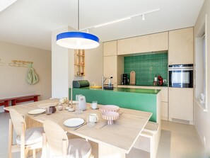 A modern kitchen with a green backsplash, wooden cabinets, and a central island with bar stools. - Holiday Home Marie Located a Stone's Throw From the Shopping Street (Koksijde)