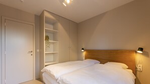 Une chambre à coucher comprenant un lit, une armoire intégrée et des lampes de chevet.