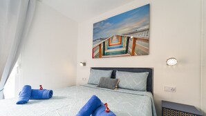 A bedroom with a bed, two pillows, a nightstand, a wall-mounted painting, and a window with curtains. - Luxury penthouse with sea views (Benidorm)