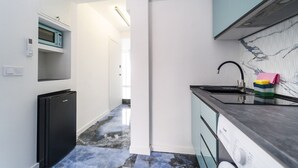 A compact kitchen with a black refrigerator, a microwave, and a sink with a marble backsplash. - Luxury penthouse with sea views (Benidorm)