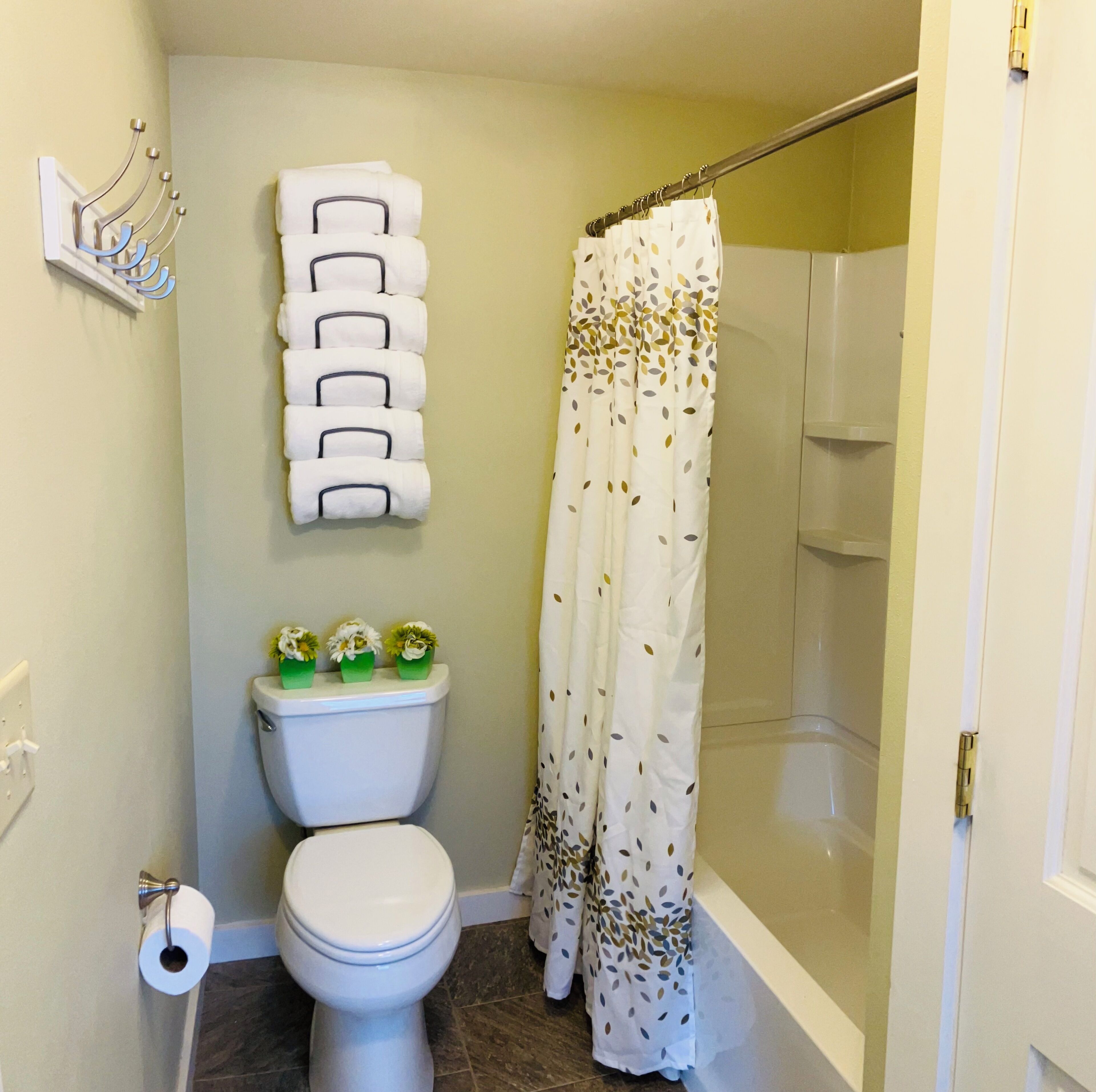 A bathroom with a toilet, a shower curtain, and a wall-mounted towel rack.