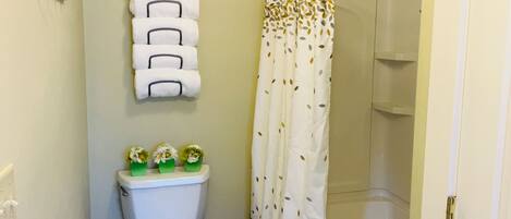 A bathroom with a toilet, a shower curtain, and a wall-mounted towel rack.