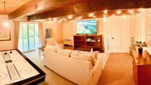 A cozy living room with a foosball table, a large flat-screen TV, a sofa, and a wooden ceiling. - >>The Daydream Lodge<<
@Racers Ridge (Plymouth)