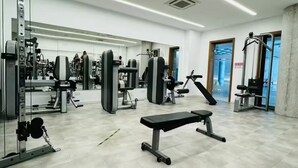A gym with various exercise equipment, a bench, and a mirrored wall. - Elysia Park B7- Luxury 2BR with Private Balcony & Resort Pools, gym-Free parking (Paphos)