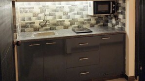 Una cocina moderna con protector de piedra, armarios oscuros y microondas integrado.