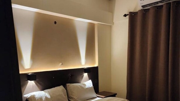 Una habitación de hotel con una cama grande, un ventilador de techo y un equipo de aire acondicionado.