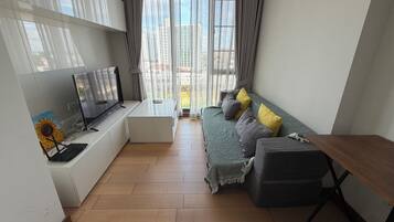 A modern living room with a sofa, a TV, and a wooden table.