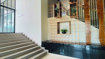 A staircase with a black marble finish, wooden railings, and potted plants.