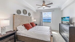 Ein Schlafzimmer mit Bett, Deckenventilator, Kommode und Fenster mit Blick.