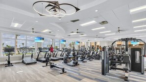 Ein modernes Fitnessstudio mit unterschiedlichen Trainingsgeräten, großen Fenstern und Blick auf Palmen.