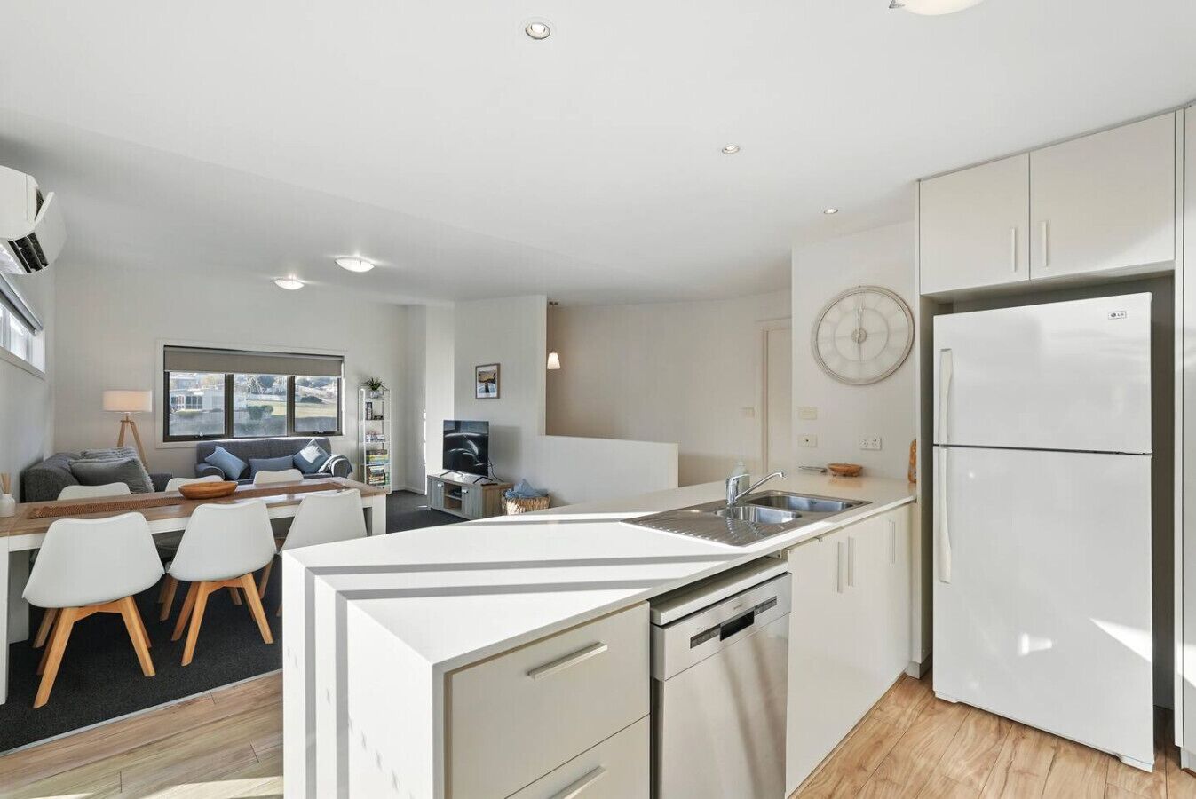 A modern kitchen with white cabinetry, a built-in dishwasher, and a refrigerator.
