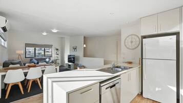 A modern kitchen with white cabinetry, a built-in dishwasher, and a refrigerator.