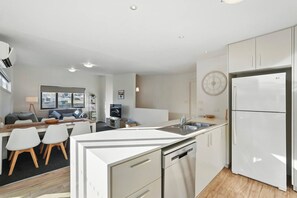 A modern kitchen with white cabinetry, a built-in dishwasher, and a refrigerator. - Spacious Modern Home (Geilston Bay)