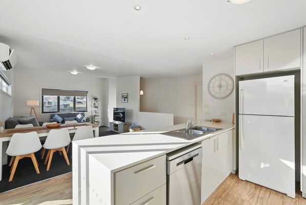A modern kitchen with white cabinetry, a built-in dishwasher, and a double sink.