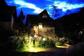 A stone house with a sloped roof and a lit entrance. - Heaven House Villa (Sa Pa)