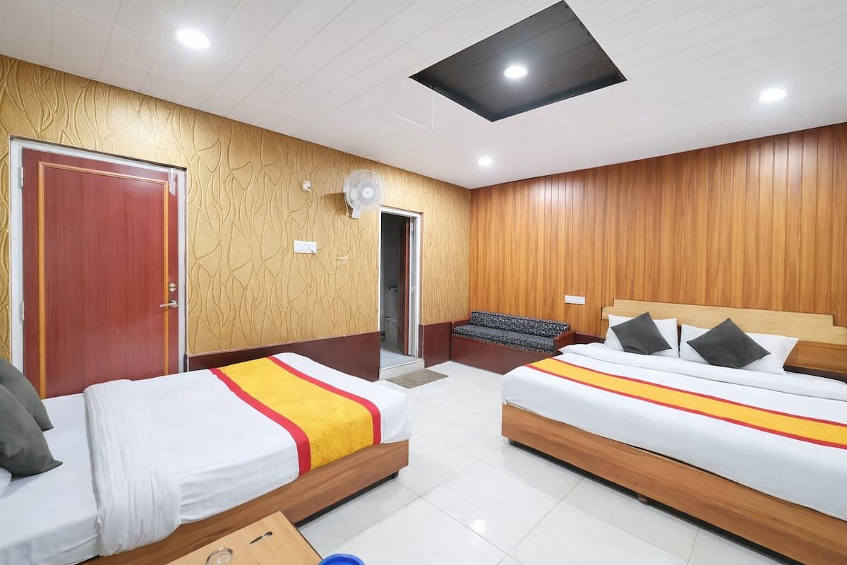 Een hotelkamer met twee bedden, een houten wandpaneel, een plafondventilator en een deur.