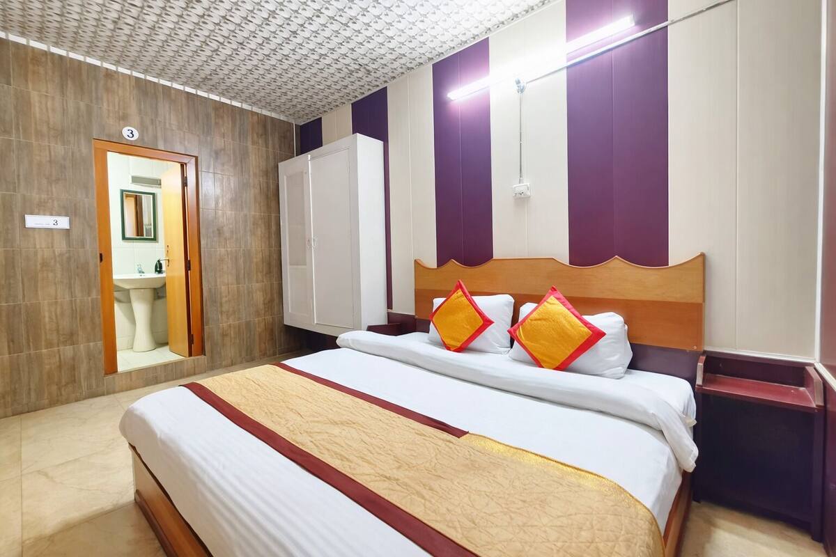 Hotelkamer met een bed, een kledingkast, een spiegel en een badkamer die door een open deur zichtbaar is.
