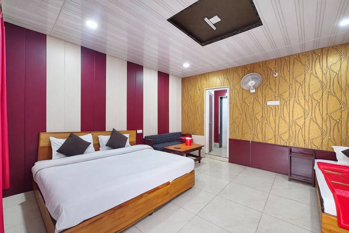 Een hotelkamer met een groot bed, een bank, een kleine tafel en een spiegel.