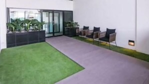 An indoor patio with artificial grass, seating, and potted plants.