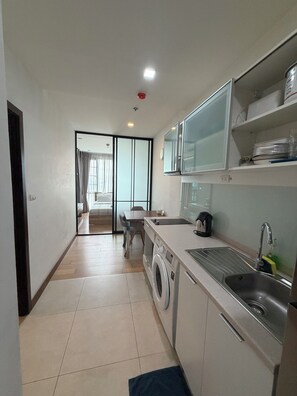 Eine kompakte Küche mit Waschmaschine, Spüle und Essbereich inklusive Tisch und Stühlen.