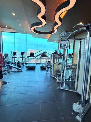 A gym with exercise equipment, a large window, and a view of buildings.